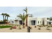 Modern home with white brick, desert landscaping, black awnings, and striking palm trees at 7001 E Joan De Arc Ave, Scottsdale, AZ 85254