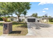 Charming single-story home featuring a large driveway, mature landscaping, and a two-car garage at 1018 W State Ave, Phoenix, AZ 85012