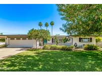 Charming single-story home with a well-manicured lawn and palm trees under a clear blue sky at 1423 E 1St St, Mesa, AZ 85203