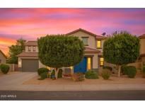 Charming home with a well-maintained lawn, mature trees, and a welcoming blue front door at 15148 W Sells Dr, Goodyear, AZ 85395