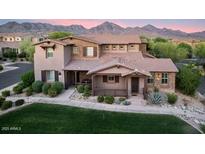Charming two-story home showcasing stone accents, a covered porch, and a well-maintained lawn set against a mountain backdrop at 18562 N 94Th St, Scottsdale, AZ 85255