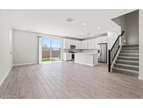Bright living room with modern kitchen, stainless appliances, tile flooring, and sliding door to backyard at 21047 N 58Th Way, Phoenix, AZ 85054