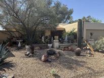 Southwest home featuring desert landscaping with rocks, cacti, and mature trees in a xeriscaped front yard at 401 W Cape Royal Ln, Phoenix, AZ 85023