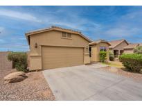 View of home's front exterior, driveway, tan paint, desert rock landscaping, and view of the roof and blue sky at 4432 W Pleasant Ln, Laveen, AZ 85339
