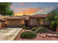 Inviting single-story home featuring desert landscaping and a tile roof, set against a vibrant sunset sky at 7617 E Desert Honeysuckle Dr, Gold Canyon, AZ 85118
