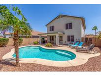 Inviting kidney-shaped pool with tanning ledge, palm tree, and outdoor dining area, perfect for relaxation at 1142 E Mayfield Dr, San Tan Valley, AZ 85143