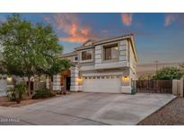 Charming two-story home with a well-manicured front yard at sunset at 14267 W Crocus Dr, Surprise, AZ 85379