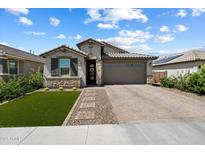 Charming home boasts stone accents, a two-car garage, and manicured landscaping at 15070 W Garfield St, Goodyear, AZ 85338