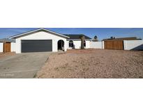 Charming single story home with a gray garage door, desert landscaping, and private fencing at 4125 W Villa Rita Dr, Glendale, AZ 85308