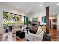 Bright living room featuring a stone fireplace, wood floors, and sliding doors to an outdoor patio at 7272 E Gainey Ranch Rd # 29, Scottsdale, AZ 85258