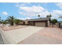 Charming single-story home with a two-car garage, desert landscaping, and a brick accent wall at 7439 E Ed Rice Ave, Mesa, AZ 85208