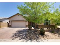Charming single-story home featuring a lush shade tree, neutral color palette, and a brick-paved driveway at 8113 S 42Nd Dr, Laveen, AZ 85339
