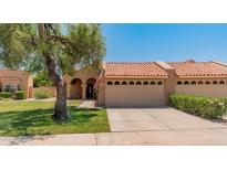 Charming home exterior with a red tile roof, well-maintained lawn, and a mature shade tree at 9125 E Gelding Dr, Scottsdale, AZ 85260