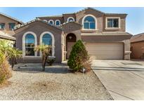 Two-story home with a two-car garage, arched windows, and low maintenance desert landscaping at 9207 W Kirby Ave, Tolleson, AZ 85353