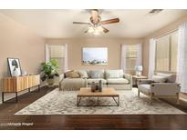 Staged living room with hardwood floors, ceiling fan, sofa, rug, side table, and decorations at 9207 W Kirby Ave, Tolleson, AZ 85353