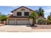 Charming two-story home with a red tile roof, a three-car garage, and mature palm trees at 987 E Divot Dr, Tempe, AZ 85283