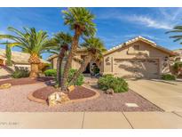 Charming single-story home with desert landscaping, palm trees, and a two-car garage at 17543 N Rainbow Cir, Surprise, AZ 85374