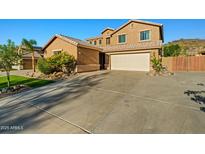 Two-story tan home with a two-car garage, desert landscaping, and a tile roof, perfect for curb appeal at 24645 N 65Th Ave, Glendale, AZ 85310