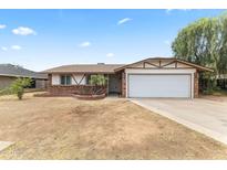 Charming single-story home featuring a two-car garage, brick accents, and a well-maintained front yard in a suburban neighborhood at 2633 E Garnet Ave, Mesa, AZ 85204