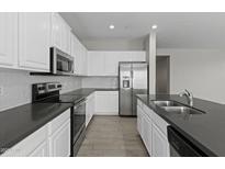 Modern kitchen with stainless steel appliances, white cabinetry, and tile flooring at 29302 N 126Th Ln, Peoria, AZ 85383