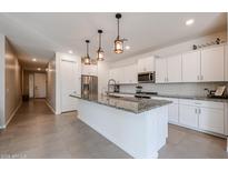 Bright kitchen features white cabinets, granite countertops, stainless appliances, and stylish pendant lighting at 4593 W Bush Bean Way, San Tan Valley, AZ 85144