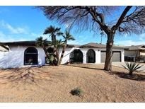 Charming home featuring an arched entryway, desert landscaping, and a two-car garage at 6254 E Winchcomb Dr, Scottsdale, AZ 85254