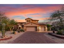 Elegant two-story home with a three-car garage, desert landscaping, and a paver driveway at sunset at 9753 E Suncrest Rd, Scottsdale, AZ 85262