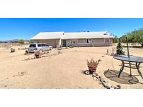 Single story home with a light colored roof and stucco walls, on a large dirt lot with car parked out front at 22222 W Lower Buckeye Rd, Buckeye, AZ 85326