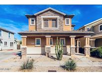 Inviting two-story home featuring a stone facade, covered porch with stone pillars, and desert landscaping in the front yard at 34913 N 30Th Dr, Phoenix, AZ 85086
