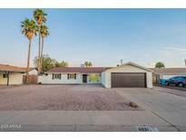 Charming single-story home with a two-car garage, desert landscaping and blue skies at 4031 W Palmaire Dr, Phoenix, AZ 85051