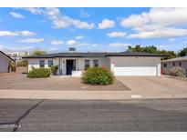 Charming single-story home with well-kept landscaping, a tidy white exterior, and a spacious two-car garage at 635 N 67Th Pl, Mesa, AZ 85205