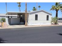 Exterior view of a manufactured home featuring a carport, desert landscaping, and a light-colored facade at 7807 E Main St # G-23, Mesa, AZ 85207