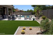 Inviting backyard featuring a pool, lush landscaping, an outdoor seating area, and artificial grass at 7940 E Quill Ln, Scottsdale, AZ 85255
