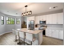 Bright kitchen with white cabinetry, stainless steel appliances, and a large island with seating for four, complemented by modern lighting at 2604 N 27Th St # 4, Phoenix, AZ 85008