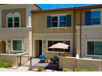 Charming two-story townhouse with tan stucco exterior and a cozy front patio with blue chairs and a small table at 2628 S Voyager Dr # 104, Gilbert, AZ 85295