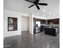 Modern kitchen featuring stainless steel appliances, dark cabinetry, and a center island, complemented by tile flooring and a ceiling fan at 3113 E Danbury Rd # 10, Phoenix, AZ 85032