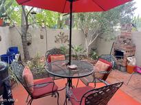 Charming patio featuring a red umbrella, outdoor seating, and a brick fireplace at 4201 E Camelback Rd # 51, Phoenix, AZ 85018