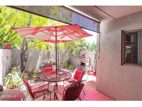 Charming outdoor patio with dining set, shade umbrella, fireplace, and view of lush backyard landscaping at 4201 E Camelback Rd # 51, Phoenix, AZ 85018