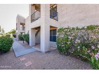 View of a residential two-story building exterior featuring a walkway and blooming bushes in a gravel yard at 14910 N Kings Way # 105, Fountain Hills, AZ 85268