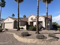 Charming single-story home with desert landscaping, featuring tall palm trees and a neutral color palette at 15314 W Camino Estrella Dr, Surprise, AZ 85374