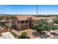 Two-story home with a brick driveway, three-car garage, and desert landscaping at 23081 S 223Rd Way, Queen Creek, AZ 85142