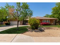 Beautiful single-story home with a well-manicured lawn, colorful flowering bushes, and a two car garage at 4404 W Olney Ave, Laveen, AZ 85339