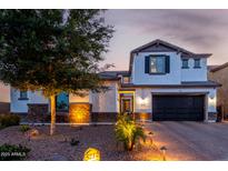 Elegant two-story home featuring a dark garage door, stucco siding, stone accents, and professional desert landscaping at 5212 S Seton Ct, Gilbert, AZ 85298