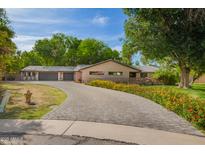 Charming home featuring a large, gray brick driveway and lush landscaping with colorful flowers at 8302 S Jentilly Ln, Tempe, AZ 85284