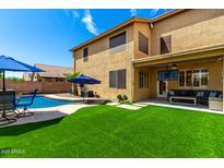 Spacious backyard with artificial turf, covered patio, outdoor TV, and a sparkling pool for ultimate outdoor living at 16565 W Garfield St, Goodyear, AZ 85338