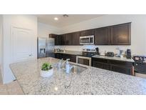 This kitchen boasts stainless steel appliances, granite countertops, and dark cabinets, creating a modern and stylish space at 17851 N Mughetto Dr, Maricopa, AZ 85138