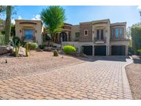 Spacious home featuring a three-car garage, decorative stone accents, and professionally landscaped desert-style yard at 18425 W Santa Irene Dr, Goodyear, AZ 85338
