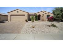 Inviting single-story home showcasing a well-kept desert landscape and brick-paved driveway at 19714 N Concord Dr, Surprise, AZ 85374