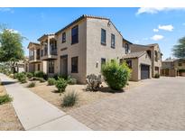 Charming stucco home with a balcony, well-maintained landscaping, and a brick driveway leading to an attached garage at 2363 W Dusty Wren Dr, Phoenix, AZ 85085