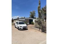 Exterior view of home with a white car parked in the driveway and mature cactus and landscaping at 318 N 83Rd Pl, Mesa, AZ 85207